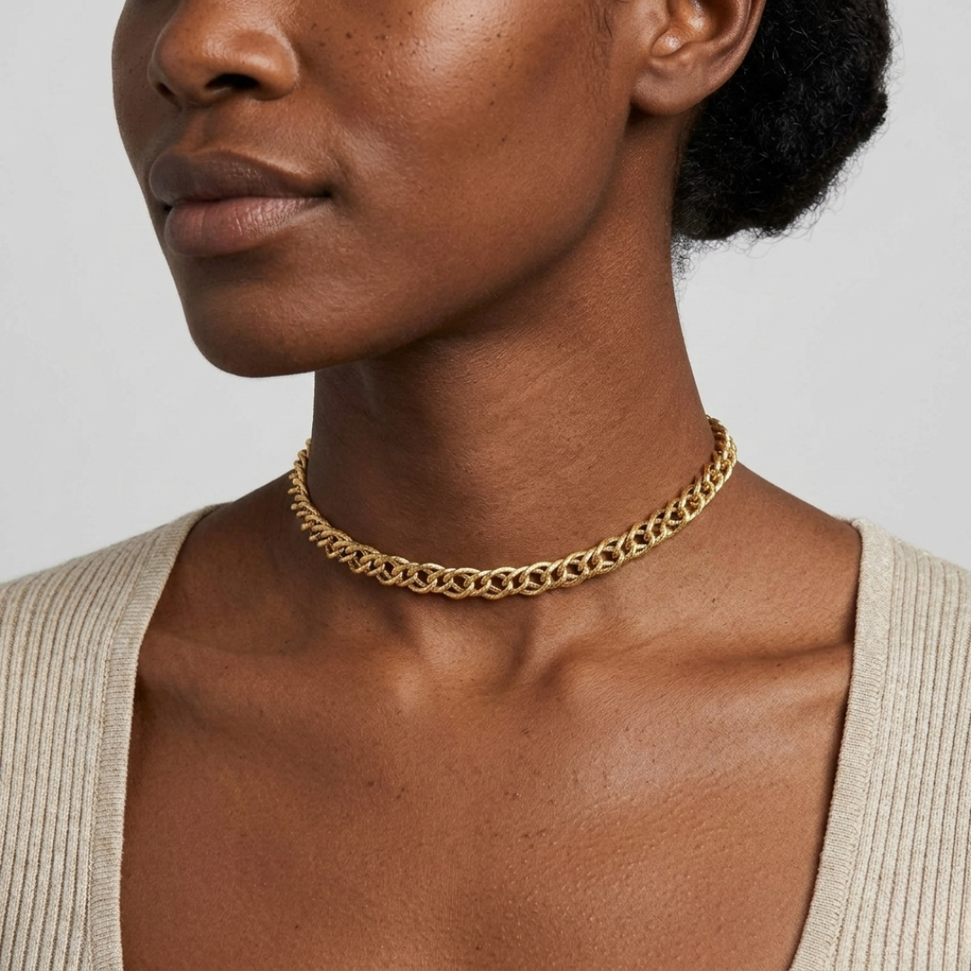 Woman wearing a gold chain choker necklace against a neutral background