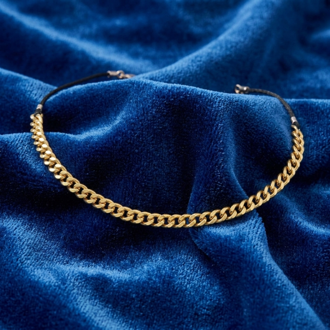 Gold chain choker necklace on a blue textured fabric background