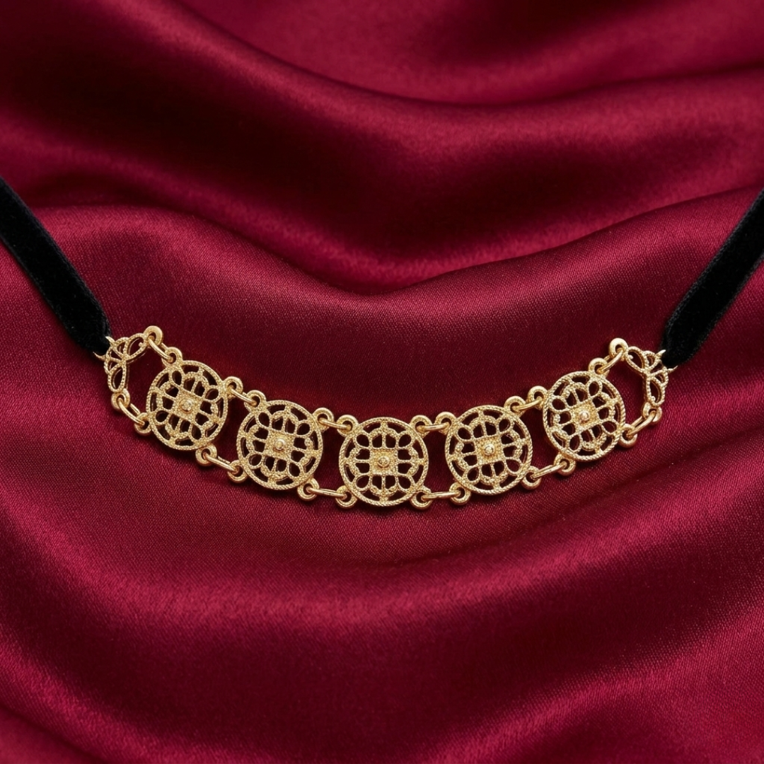 Gold choker necklace on a red satin background