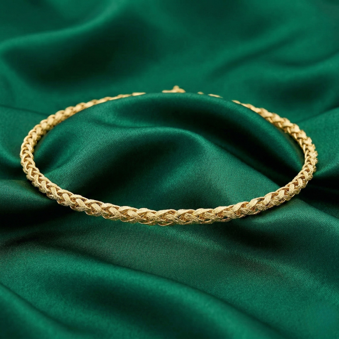 Gold braided choker necklace on a green fabric background