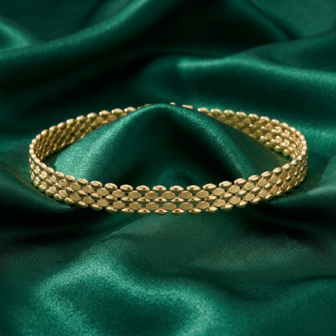 Gold choker necklace on a green satin background