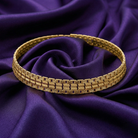 Gold choker necklace on a purple fabric background