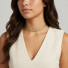 Woman wearing a gold choker necklace with a plain background