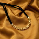 Gold braided choker necklace on a brown fabric background