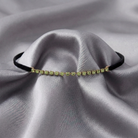 Green crystal choker necklace on a black velvet cord on gray fabric