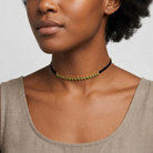 Woman wearing a green crystal choker necklace on a plain background