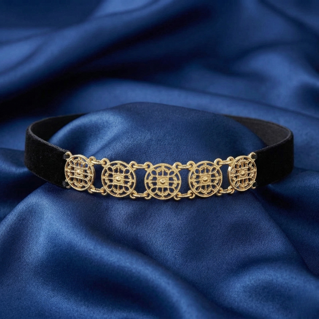 Gold choker necklace on a blue fabric background