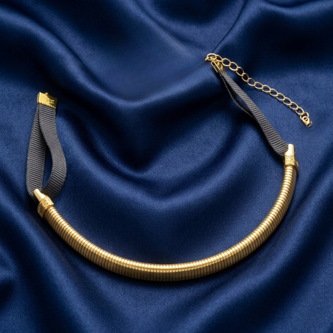 Gold choker necklace on a blue satin background