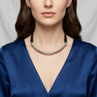 Woman wearing a blue top and silver cobra choker necklace against a neutral background