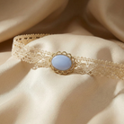 Delicate lace choker with a light blue stone on a beige fabric background