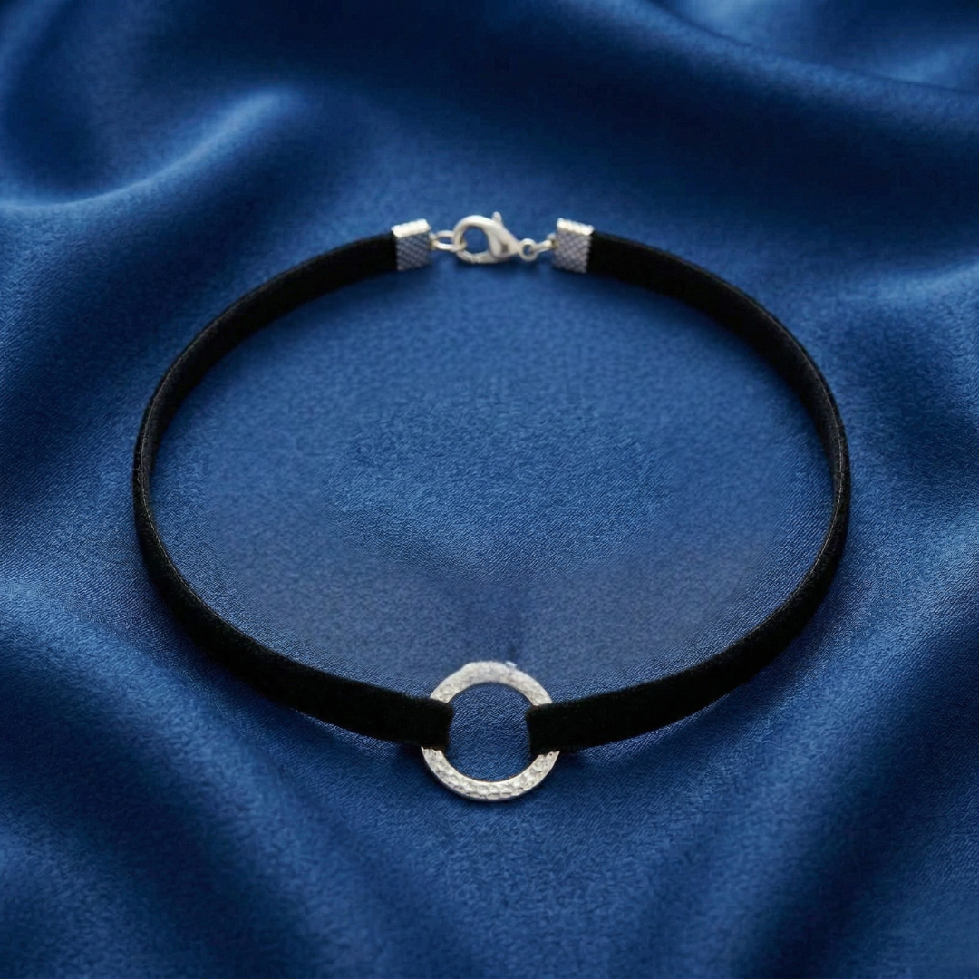 Black choker necklace with silver clasp on a blue fabric background