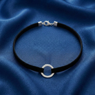 Black choker necklace with silver clasp on a blue fabric background