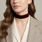 Woman wearing a burgundy velvet choker with a neutral background