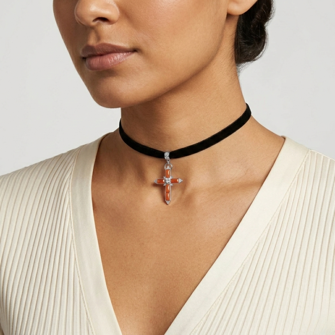 Woman wearing a black choker with a silver cross pendant on a plain background