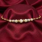 Faux pearl bracelet with gold accents on a red fabric background