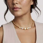 Close-up of a woman wearing a faux pearl necklace against a neutral background