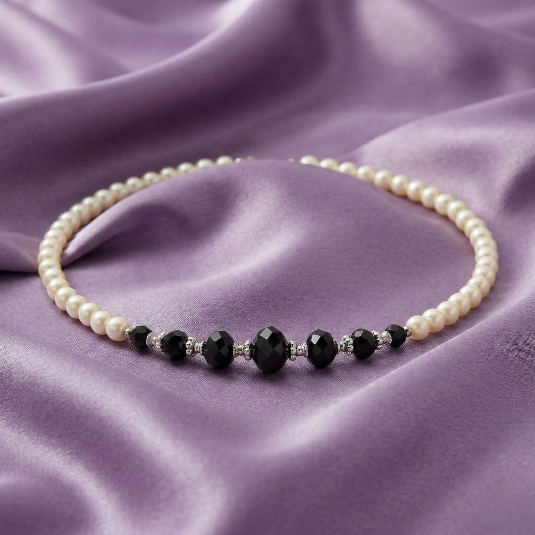Pearl necklace with black beads on a purple fabric background