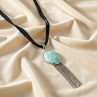 Necklace with turquoise pendant and tassel on beige fabric