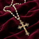 Faux Pearl Chain Gold Crucifix Cross Pendant Necklace against a burgundy fabric background