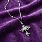 Filigree Cross With Faux Pearl Crystal Accent Pendant Necklace on a purple fabric background
