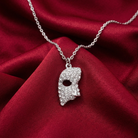 Silver necklace with a masquerade mask pendant lined filled with crystals on a red fabric background