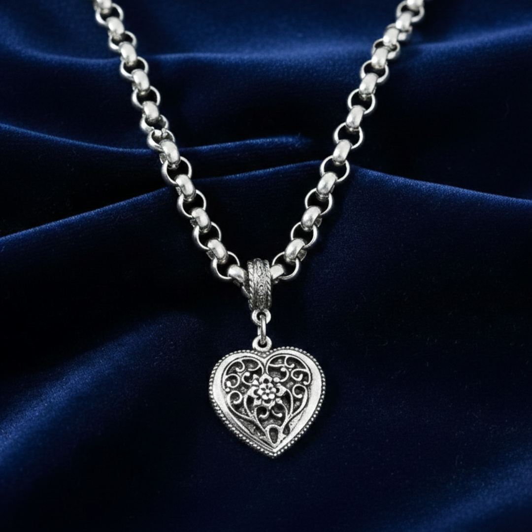 Silver chain necklace with a heart-shaped pendant on a dark blue fabric background