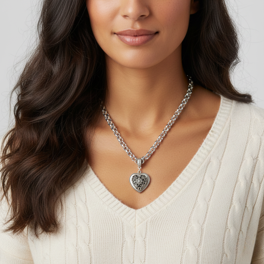 Woman wearing a silver necklace with a heart pendant against a neutral background