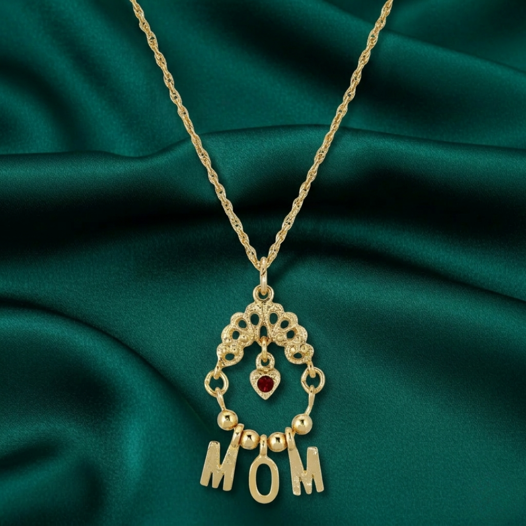 Gold necklace with 'MOM' pendant on a green fabric background