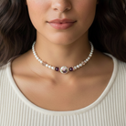 Faux pearl necklace with a central gemstone worn by a model. 