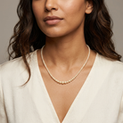 Woman wearing a faux pearl necklace against a neutral background