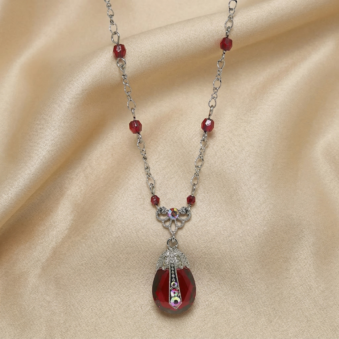 Necklace with a red teardrop pendant on a beige fabric background