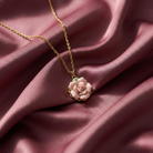 Gold necklace with a pink flower rose pendant on a pink fabric background