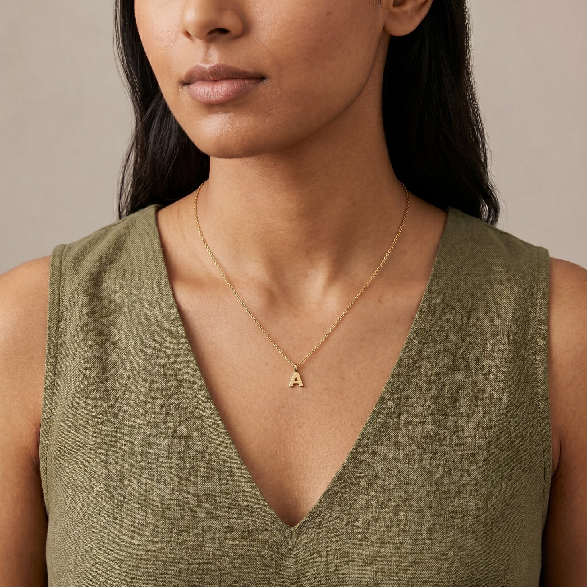 Woman in a green top wearing a gold tone Initial Letter "A" Pendant Necklace