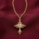 Gold necklace with a cross pendant featuring a porcelain rose on a red background