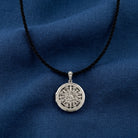Silver necklace with a round locket pendant on a blue fabric background