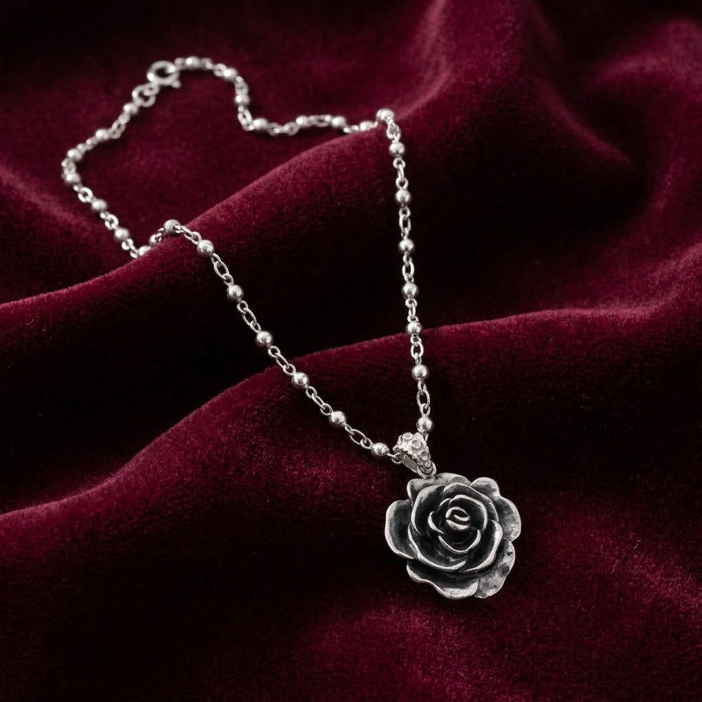 Silver rose necklace on a burgundy fabric background