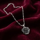 Silver rose necklace on a burgundy fabric background