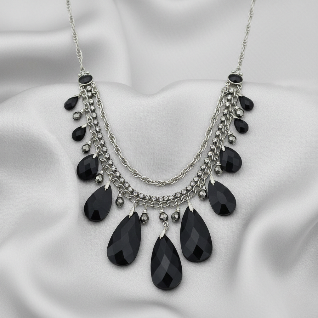 Necklace with black teardrop-shaped pendants on a white fabric background