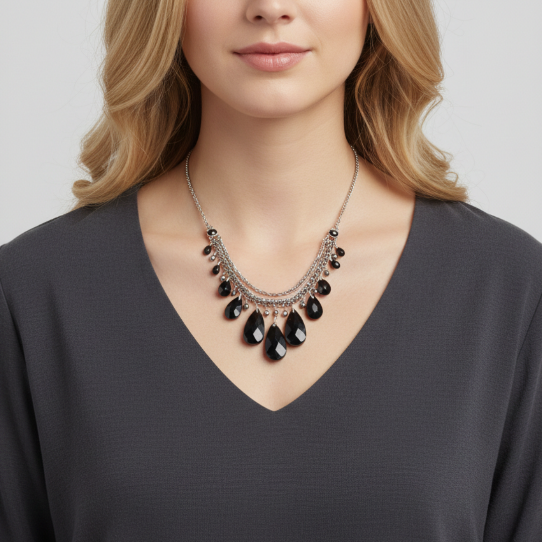 Woman wearing a black teardrop necklace on a plain background