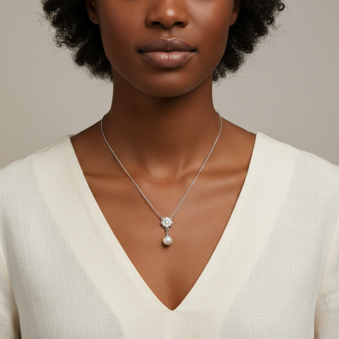 Woman wearing a necklace with a crystal and faux pearl pendant against a neutral background
