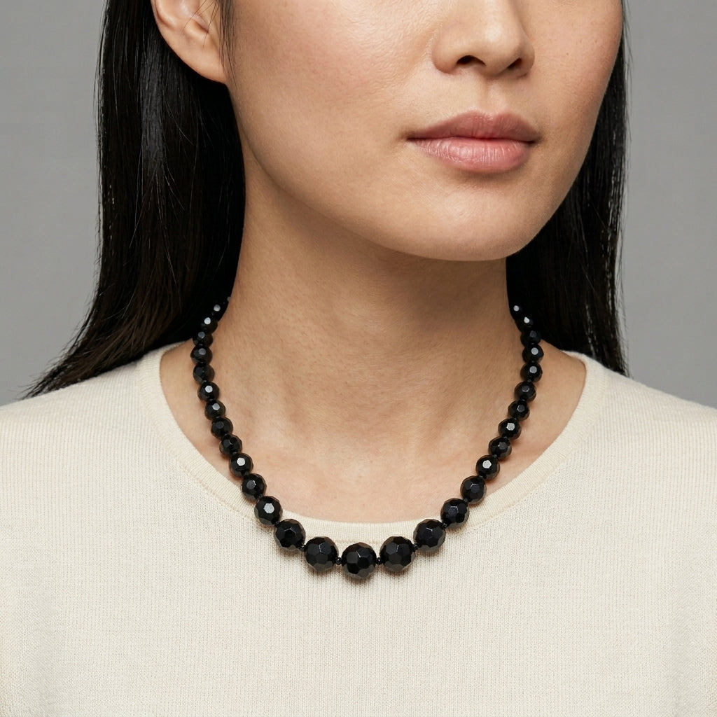 Woman wearing a black beaded necklace against a neutral background
