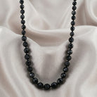 Black beaded necklace on a beige fabric background