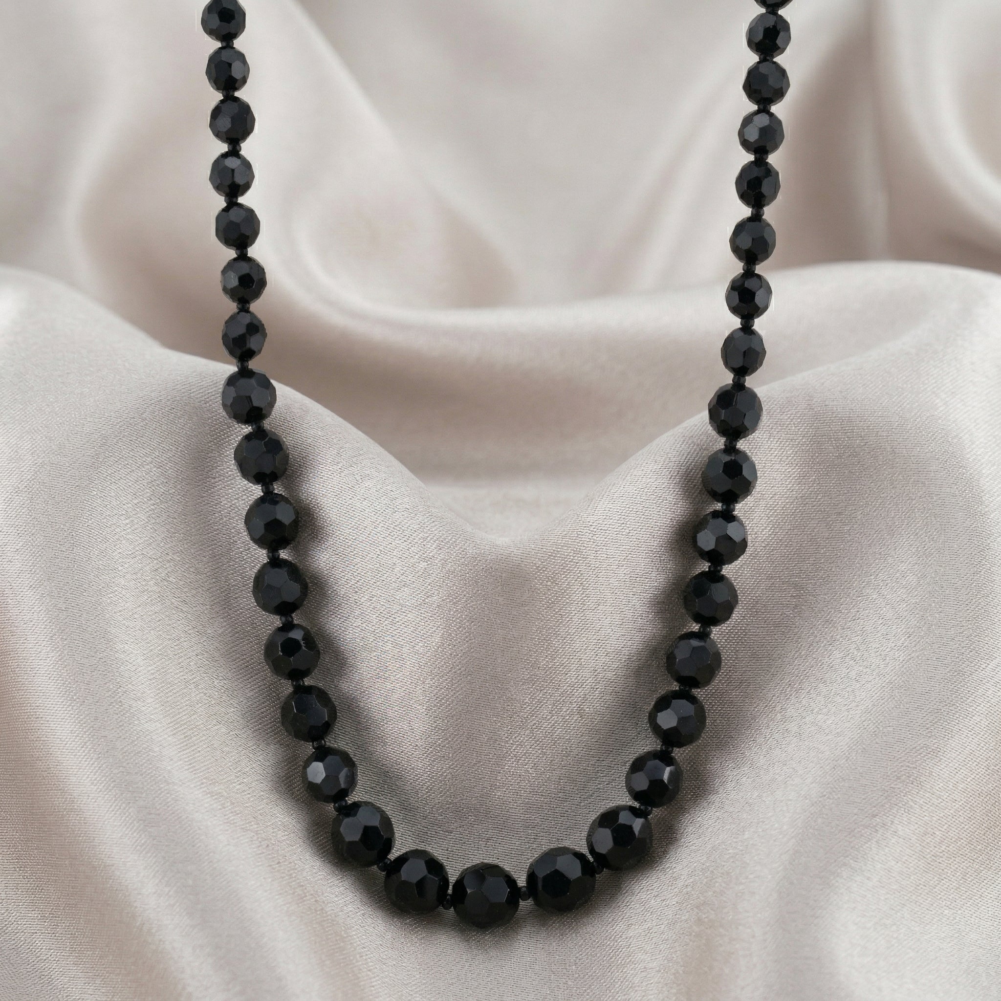 Black beaded necklace on a beige fabric background