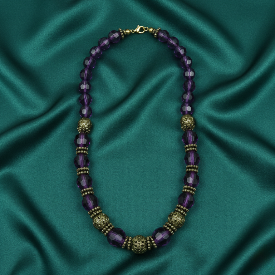 Purple beaded necklace with gold accents on a teal satin background