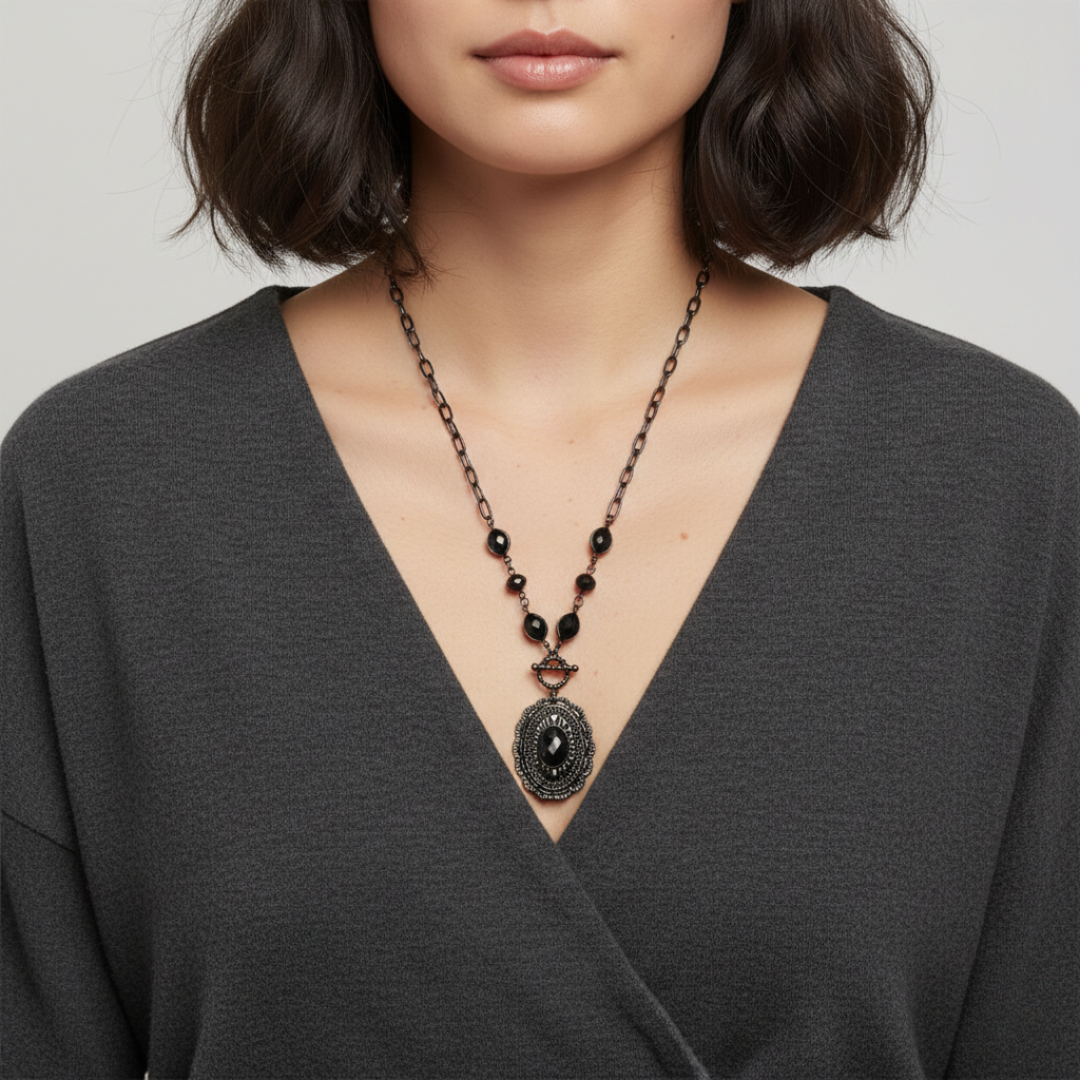 Woman wearing a black beaded necklace with a pendant on a plain background