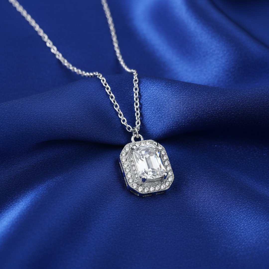 Silver necklace with a large clear crystal pendant on blue satin fabric