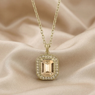 Gold necklace with a pendant on a beige fabric background