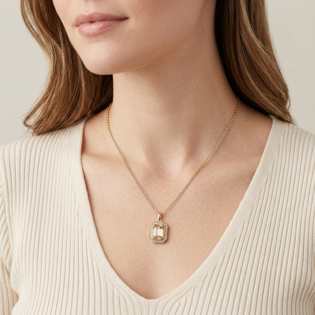 Gold necklace with a pendant worn by a person in a beige top against a neutral background
