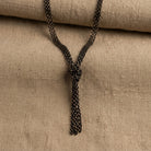 Eclipse Black And Gold Chain Tassel Knotted Necklace 16" + 3" Extender resting on tan fabric