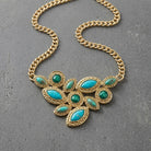 Gold necklace with turquoise stones on a gray surface